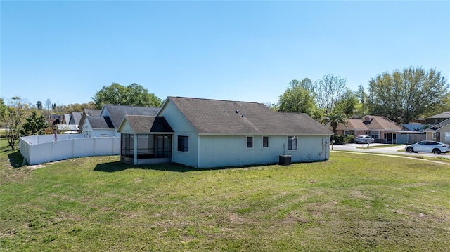 back of property with fence, a lawn, and a sunroom