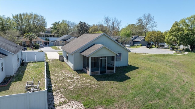 exterior space featuring a residential view, a lawn, fence, and a sunroom