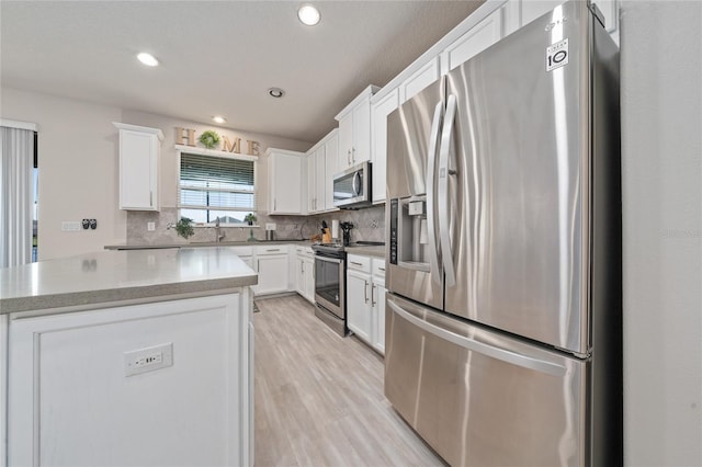 kitchen featuring decorative backsplash, white cabinets, and stainless steel appliances