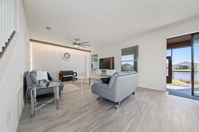 living area featuring light wood-style flooring, baseboards, visible vents, and ceiling fan