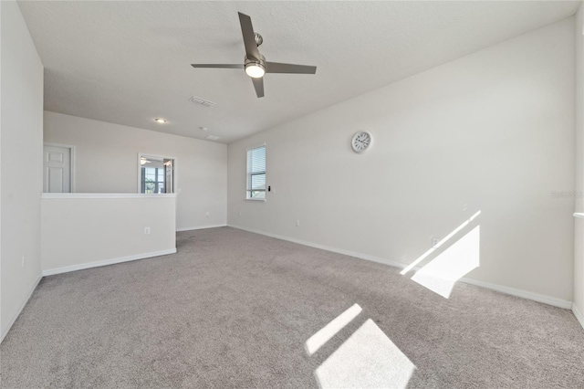 empty room with visible vents, baseboards, a ceiling fan, and carpet floors