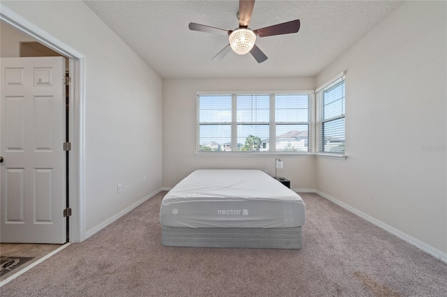 bedroom with ceiling fan, baseboards, carpet floors, and a textured ceiling