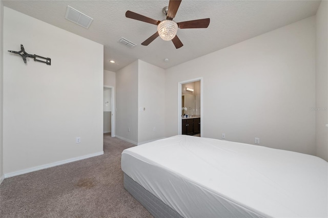 carpeted bedroom featuring visible vents, a textured ceiling, ensuite bathroom, and baseboards