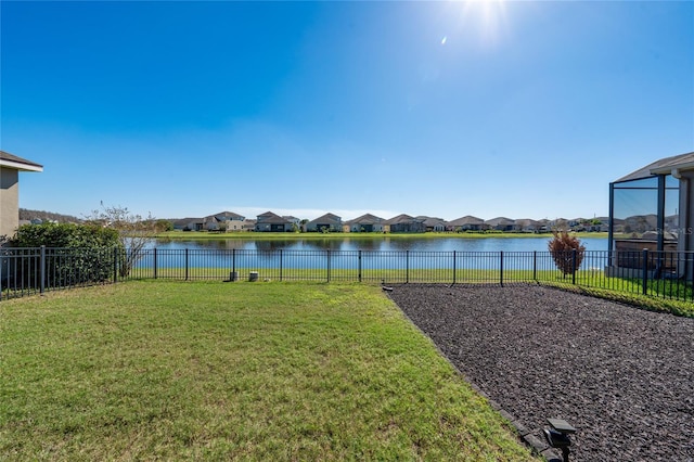 view of yard featuring a residential view, a fenced backyard, and a water view