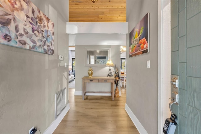 hall featuring a healthy amount of sunlight, wood finished floors, visible vents, and baseboards