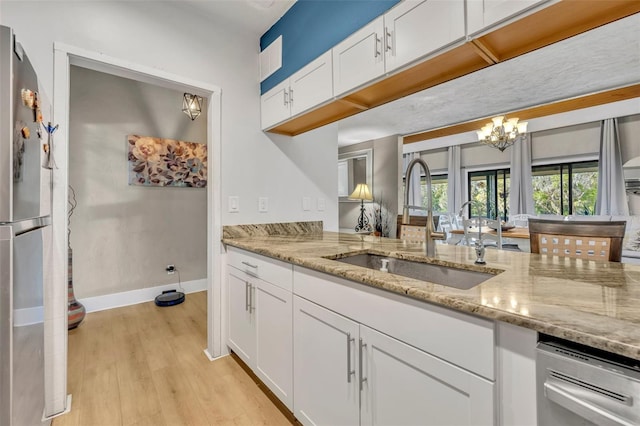 kitchen featuring light wood-type flooring, a sink, white cabinetry, freestanding refrigerator, and an inviting chandelier