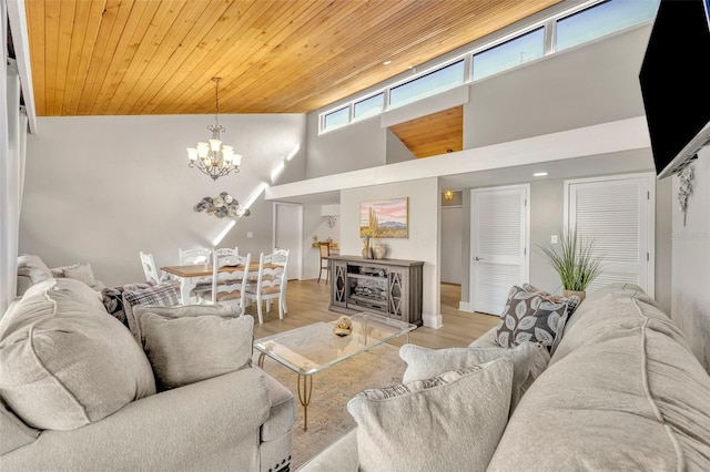 living area with an inviting chandelier, a high ceiling, light wood finished floors, and wooden ceiling