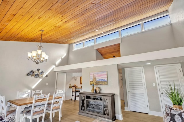 dining space with an inviting chandelier, a high ceiling, wood finished floors, and wooden ceiling