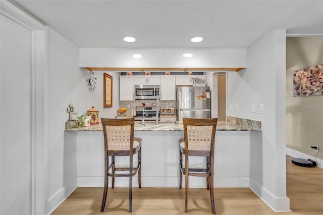 kitchen with light wood-style flooring, appliances with stainless steel finishes, and a peninsula