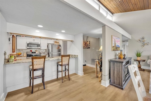 kitchen featuring light wood-type flooring, visible vents, backsplash, stainless steel appliances, and a peninsula