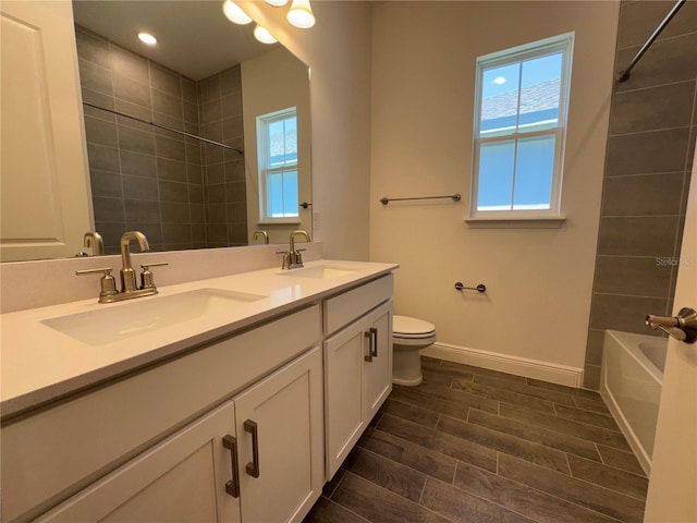 bathroom featuring wood tiled floor, toilet, baseboards, and a sink