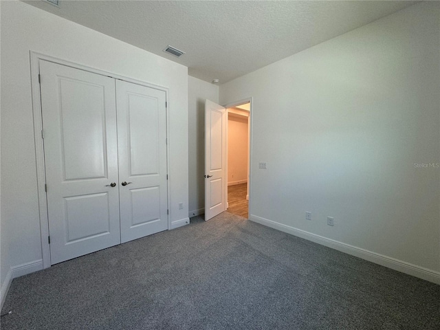 unfurnished bedroom featuring carpet, baseboards, visible vents, a closet, and a textured ceiling