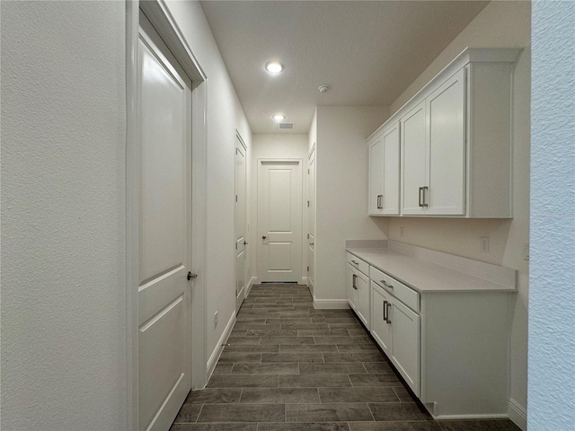 hall with recessed lighting, a textured wall, baseboards, and wood finish floors