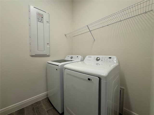 laundry room featuring baseboards, wood tiled floor, laundry area, electric panel, and separate washer and dryer