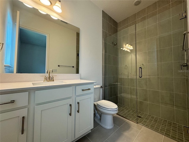 bathroom with visible vents, toilet, a stall shower, tile patterned flooring, and vanity