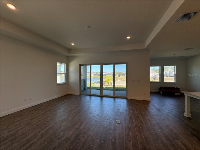 unfurnished room featuring visible vents, baseboards, recessed lighting, a raised ceiling, and dark wood-style flooring