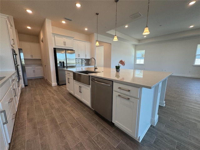 kitchen with a center island with sink, a sink, white cabinetry, appliances with stainless steel finishes, and wood tiled floor