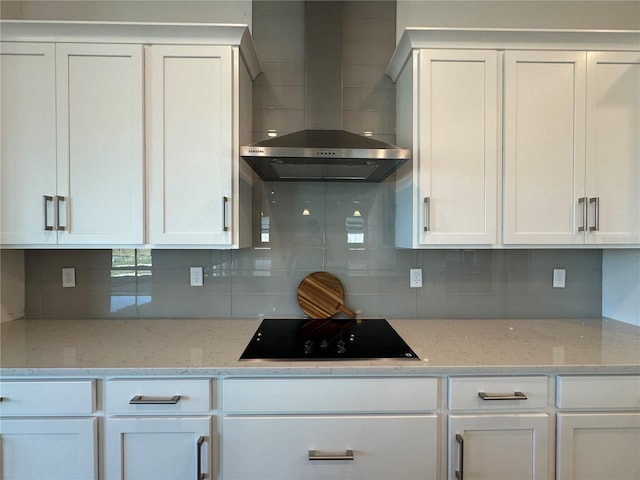 kitchen featuring decorative backsplash, black electric stovetop, white cabinetry, and wall chimney range hood