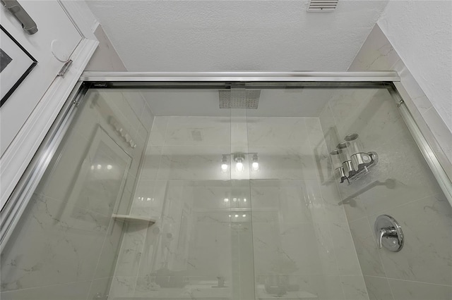 full bathroom featuring a shower stall, visible vents, and a textured ceiling