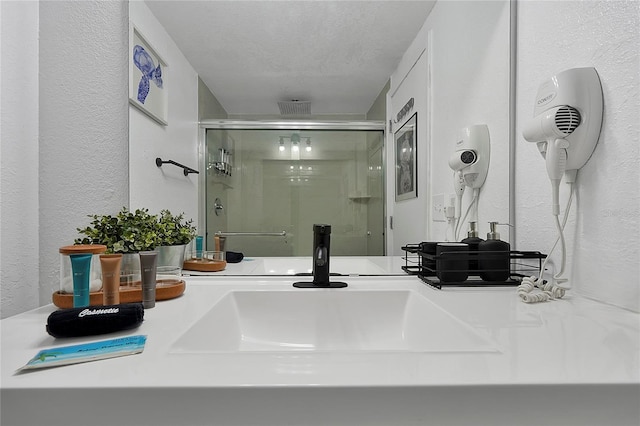 details with a shower stall, a textured ceiling, vanity, and a textured wall