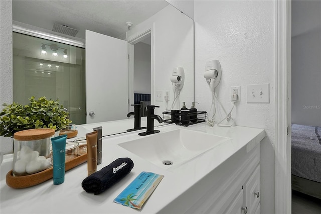 full bathroom featuring visible vents, a stall shower, vanity, and a textured wall