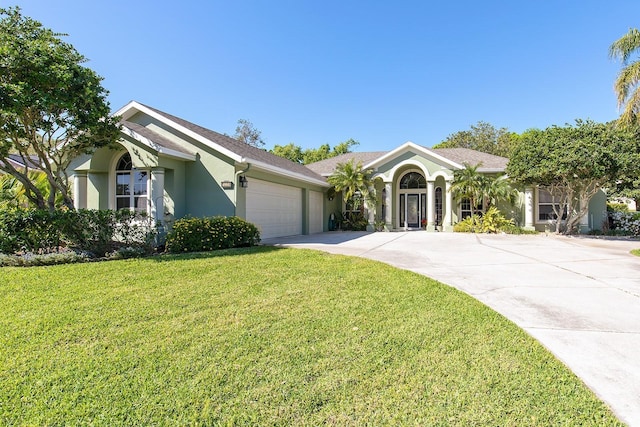 view of front of home featuring a front lawn, a garage, driveway, and stucco siding