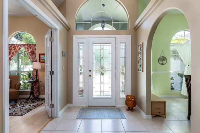 tiled entrance foyer with baseboards, a high ceiling, and arched walkways