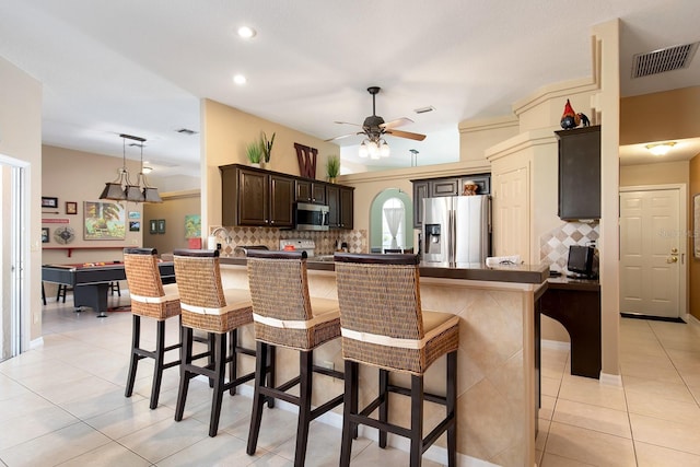 kitchen with visible vents, ceiling fan, dark brown cabinetry, a breakfast bar area, and stainless steel appliances