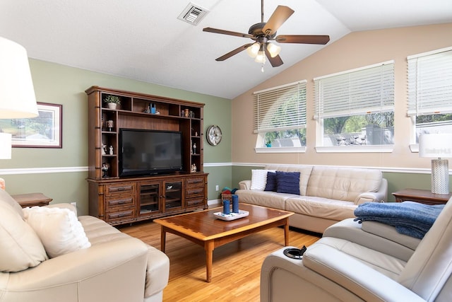 living room featuring visible vents, lofted ceiling, light wood-style floors, and a ceiling fan