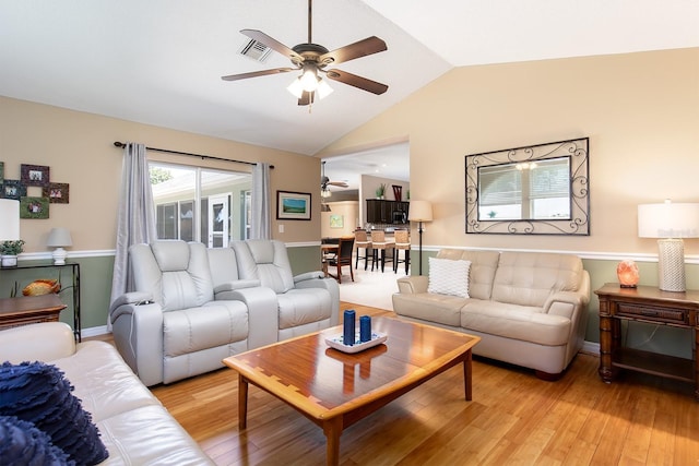 living room with light wood-type flooring, visible vents, lofted ceiling, baseboards, and ceiling fan