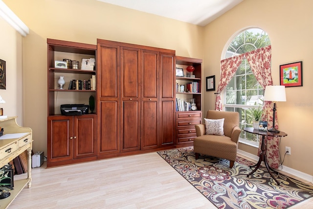 living area with light wood-type flooring, baseboards, and vaulted ceiling