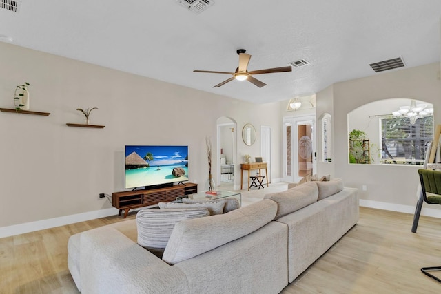 living room featuring light wood-type flooring, visible vents, and arched walkways