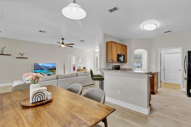 dining space featuring visible vents, light wood-style floors, and a ceiling fan