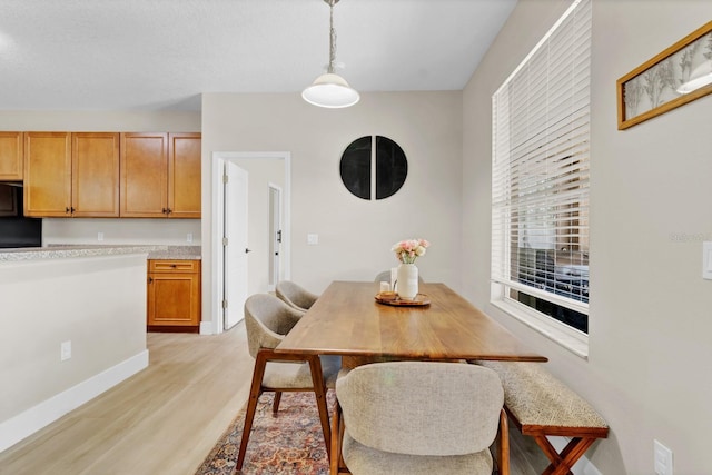 dining space with light wood finished floors and baseboards