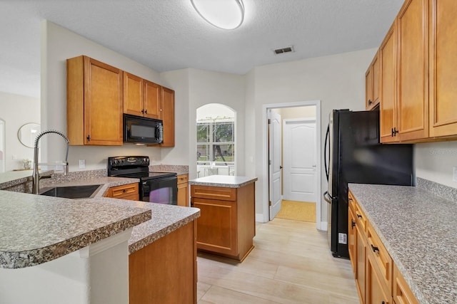 kitchen featuring visible vents, black appliances, a sink, a center island, and arched walkways