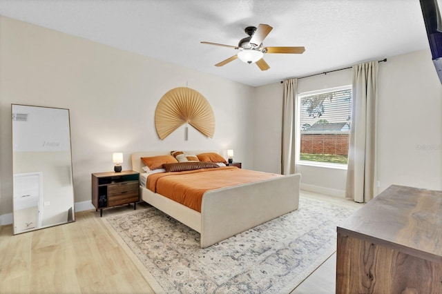 bedroom with ceiling fan, light wood-type flooring, and baseboards