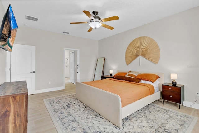 bedroom with a ceiling fan, baseboards, visible vents, and light wood finished floors