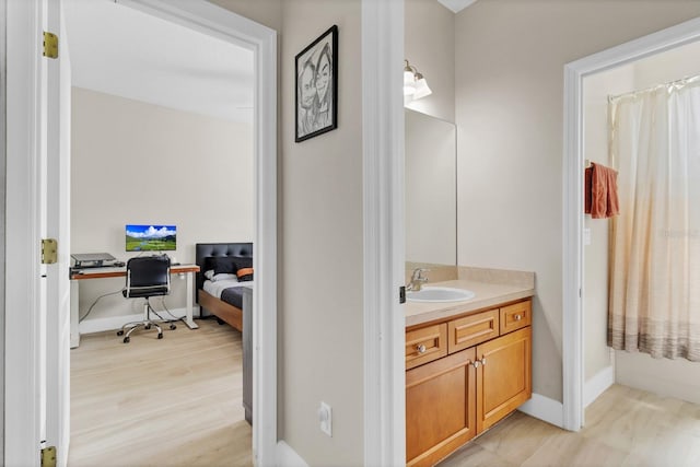 bathroom featuring baseboards, wood finished floors, and vanity