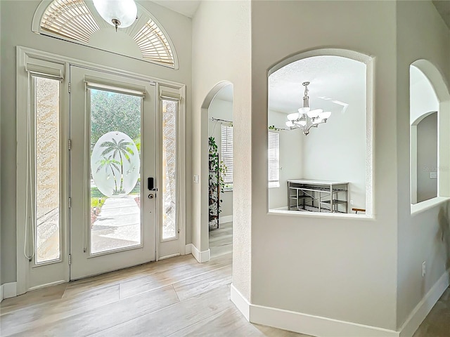foyer with an inviting chandelier, arched walkways, and baseboards