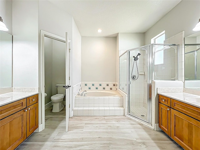 full bathroom with a garden tub, a textured ceiling, a shower stall, two vanities, and toilet