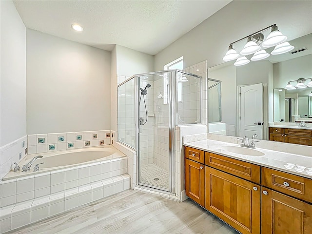 full bathroom with vanity, a shower stall, a bath, and visible vents