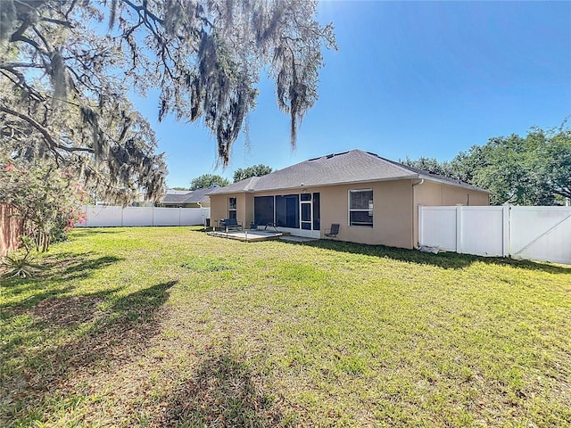 back of house featuring a fenced backyard, stucco siding, and a yard