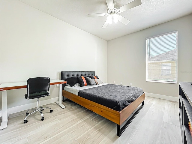 bedroom with a ceiling fan, baseboards, and light wood-style flooring