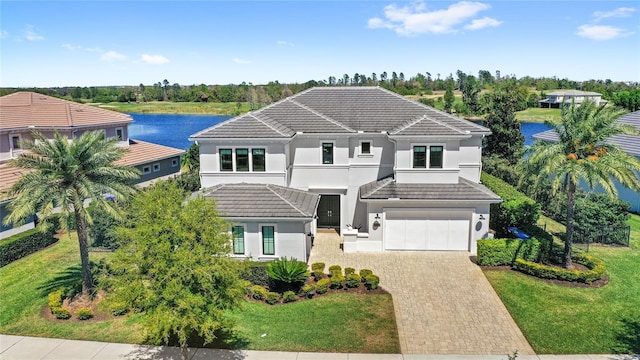 view of front of home featuring a tile roof, a front yard, stucco siding, decorative driveway, and an attached garage