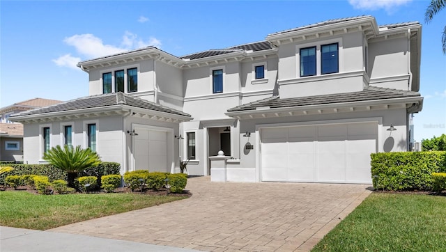 view of front of property with a tiled roof, a garage, decorative driveway, and stucco siding