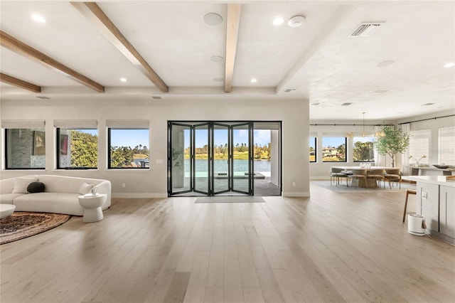 unfurnished living room with visible vents, beam ceiling, recessed lighting, light wood-style floors, and baseboards