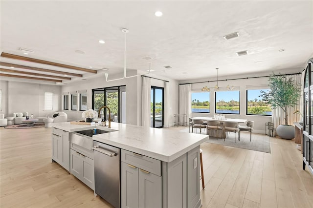 kitchen featuring a sink, gray cabinetry, open floor plan, and light wood finished floors