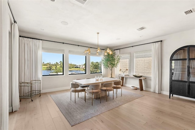 dining area featuring light wood finished floors, visible vents, baseboards, and a notable chandelier