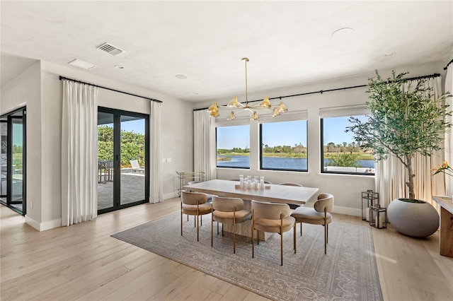 dining room with a notable chandelier, visible vents, french doors, and light wood-type flooring