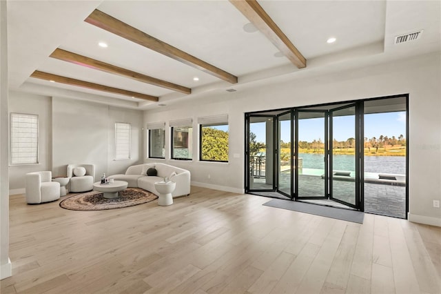 living area with visible vents, plenty of natural light, light wood-style floors, and a water view